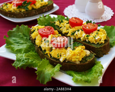 Sandwiches mit Rührei und Kirschtomaten auf hausgemachtes Brot mit Nesseln Stockfoto