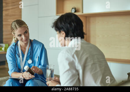 Schöne lächelnde Frau der Arzt in einer Flasche Pille bietet den Patienten. Stockfoto