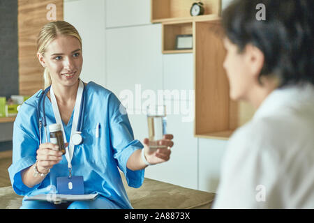 Schöne lächelnde Frau der Arzt in einer Flasche Pille bietet den Patienten. Stockfoto