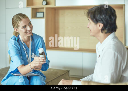 Schöne lächelnde Frau der Arzt in einer Flasche Pille bietet den Patienten. Stockfoto