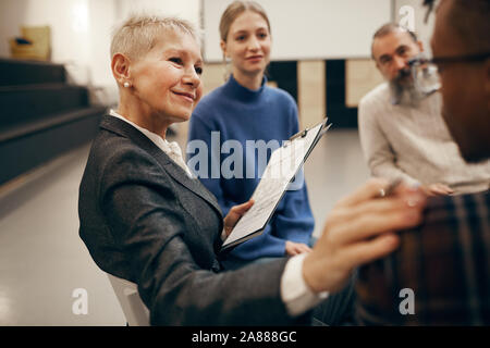 Reife Frau mit kurzen blonden Haaren zu jungen Mann sehr aufmerksam zuhören Während der Therapie Lektion Stockfoto