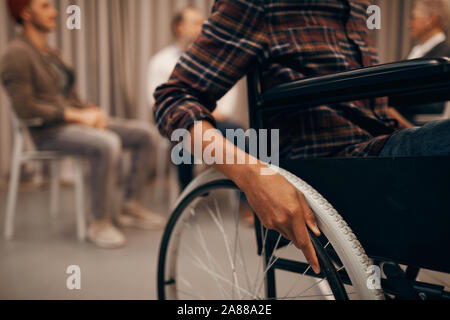 Nahaufnahme der junge Mann sitzt im Rollstuhl mit Gruppe von Menschen im Hintergrund Stockfoto