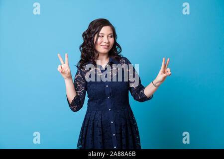 Porträt einer wunderschönen asiatischen Frau in einem blauen Kleid zeigt vier Finger Stockfoto