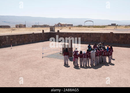 Bolivianischen Studierenden in Schuluniform beachten Sie die Anleitung auf halb-unterirdischen Tempel Eingang in Tiwanaku archäologischen Komplex, Bolivien Stockfoto