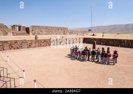 Bolivianischen Studierenden in Schuluniform beachten Sie die Anleitung auf halb-unterirdischen Tempel Eingang in Tiwanaku archäologischen Komplex, Bolivien Stockfoto