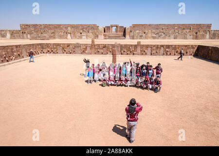 Bolivianischen Studierenden in Schuluniform auf halb-unterirdischen Tempel Eingang in Tiwanaku archäologischen Komplex, Bolivien Stockfoto