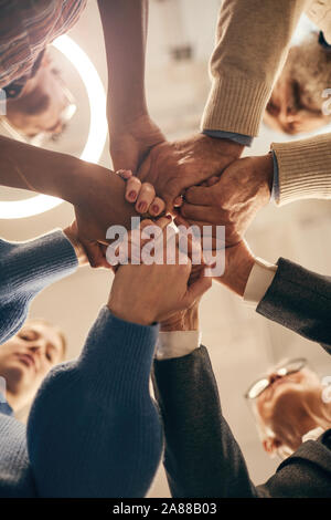 Low Angle View der Gruppe von Menschen halten sich an den Händen und Vereinen bei der Arbeit in der Team in der Sitzung Stockfoto