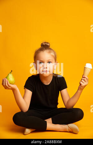 Kleine Tänzerin die Wahl zwischen Birnen und Eis verwirrt Stockfoto