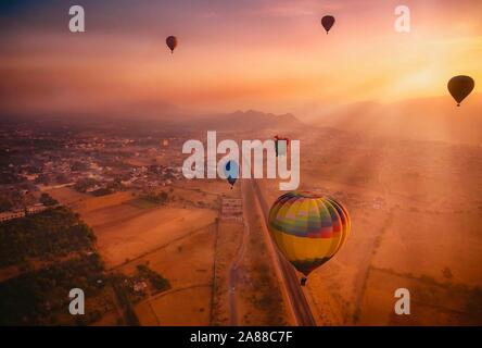 Luftaufnahme von einem Sonnenaufgang Szene, wo Sonnenstrahlen und Heißluftballons, die Touristen die bunten Himmel über Pushkar, Rajasthan füllen. Stockfoto