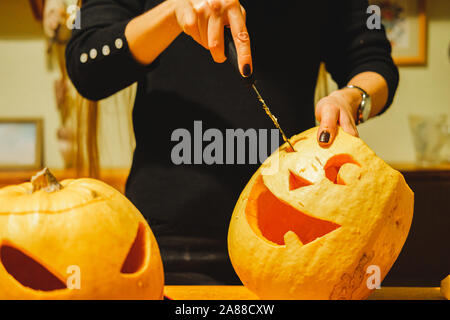 Carving Halloween Kürbisse in der Küche. Kennzeichnung und Schnitzen große Jack o'Lantern Kürbisse Stockfoto