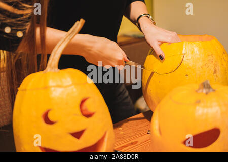 Carving Halloween Kürbisse in der Küche. Kennzeichnung und Schnitzen große Jack o'Lantern Kürbisse Stockfoto