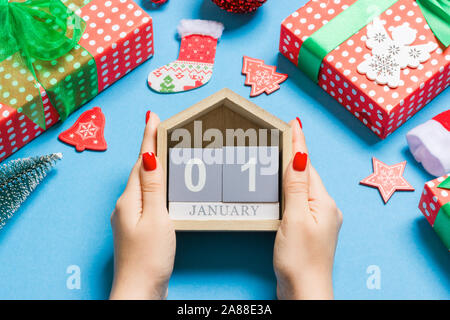 Blick von oben auf die weibliche Hände halten Kalender auf blauem Hintergrund. Der erste Januar. Urlaub Dekorationen. Neues Jahr Konzept. Stockfoto