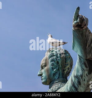 Schreien Möwe mit weit geöffneten Schnabel auf den Kopf des Charles XII Statue im Kungstradgarden, Stockholm, Schweden Stockfoto