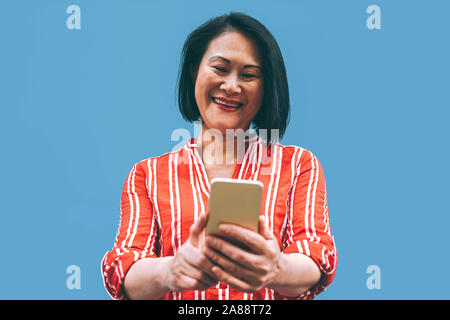 Asiatische senior Frau Spaß mit Handy Outdoor - glückliche Chinesischen weiblichen außen mit Smartphone Stockfoto