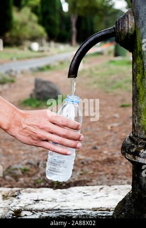 Nahaufnahme von einem jungen Mann cacausian füllen eine Plastikflasche mit Wasser aus einem Brunnen, an der Via Appia Antica Straße in Rom, Italien Stockfoto