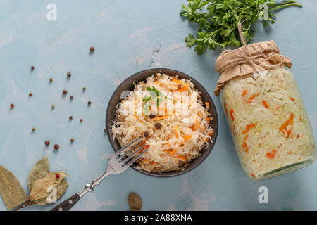 Hausgemachten Sauerkraut mit Möhren in eine Schüssel und Glas auf einem hellblauen Hintergrund, fermentierte Lebensmittel Stockfoto