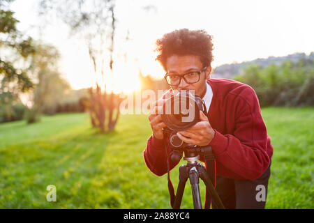 Junge Hobby Fotografen als Naturfotograf mit Kamera auf dem Stativ Stockfoto