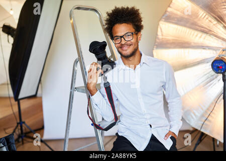 Erfolgreiche junge Mann als Fotograf im Fotostudio mit Kamera Stockfoto