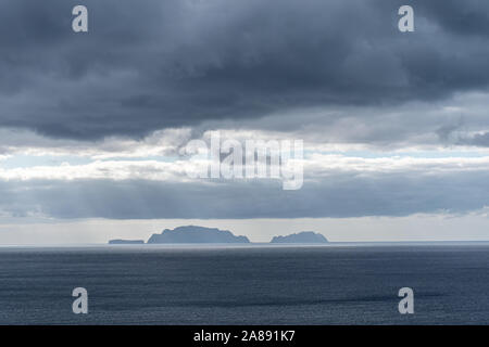 Ein Blick auf einer fernen Insel, Sonnenstrahlen, die durch dramatische stürmischen graue Wolken über Stockfoto