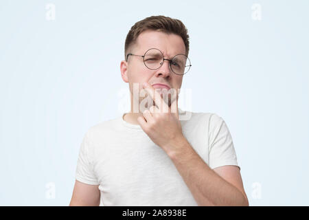 Schwere männliche Kursteilnehmer im weißen T-Shirt trägt Optische runden Brille, sieht Ernst, hat strenge fragend an, versucht, zu entscheiden, was zu tun. Studio shot Stockfoto