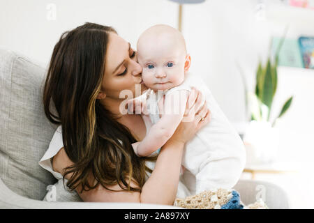 Mutter küsst die Wange ihres kleinen Jungen Stockfoto