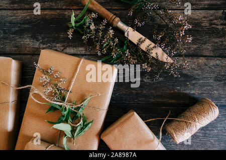 Geschenke verpackt in braunem Papier und Schnur mit Blumen und Messer Stockfoto