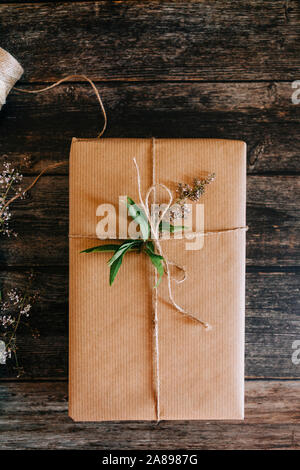 Geschenk verpackt in braunem Papier mit Schnur und Blumen Stockfoto