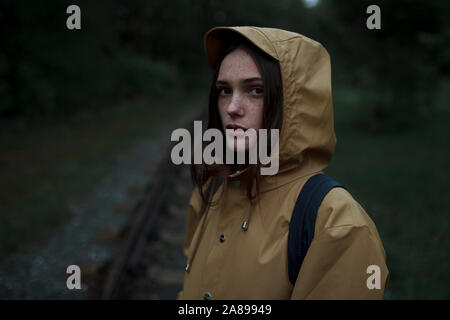 Junge Frau in braunem Regenmantel Stockfoto