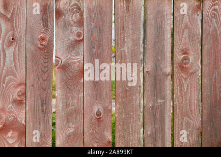 Abstrakte Holz- Textur für den Hintergrund in der Form eines alten verwitterten Lattenzaun mit verblasste rote Farbe und Lücken reißt. Geknotet Boards sind braun. Stockfoto