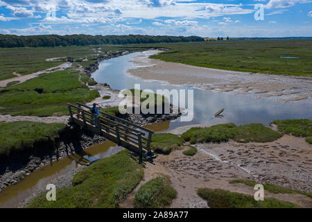 Hohe Blick auf Salzwiesen mit Walker auf der Brücke an der Küste in der Nähe von Stiffkey, Norfolk, England Stockfoto