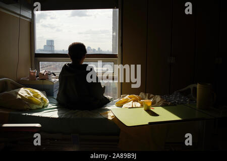 Frau am Krankenhausbett saß, drehte sich um und sah aus dem Fenster - allein Stockfoto