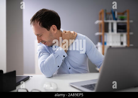 Junge Menschen leiden unter Nackenschmerzen beim Arbeiten am Laptop Stockfoto