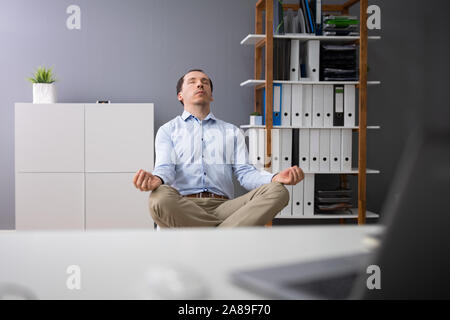 Junge Unternehmer Yoga hinter dem Schreibtisch im Büro Stockfoto