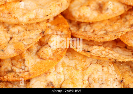 Extreme Nahaufnahme von einem Stapel von organischen, knusprige, gebackene, Vollkorn Reis Chips mit Tomaten und Paprika Gewürze. Glutenfreie gesunden Snack. Makro essen Bac Stockfoto