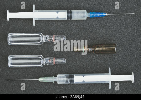 Spritzen und Durchstechflaschen mit Medizin auf Pflaster. Die Behandlung im Krankenhaus. Medizin mit flüssigem Injektionen Stockfoto