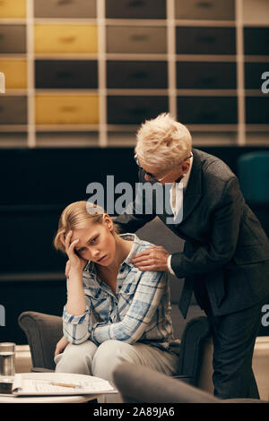 Traurige junge Frau sitzt auf einem Sofa und über ihre Probleme mit dem Psychologen umfassend und unterstützen Sie bei Office besorgt Stockfoto