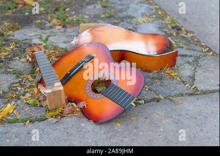 Eine kaputte alte Gitarre liegend auf dem Beton, auf einem New York City street verworfen Stockfoto