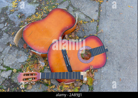 Eine kaputte alte Gitarre liegend auf dem Beton, auf einem New York City street verworfen Stockfoto