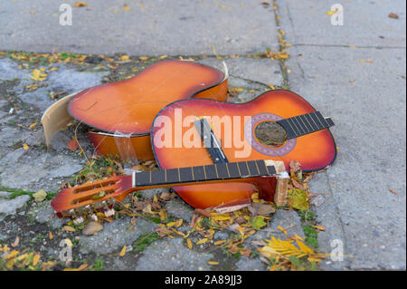 Eine kaputte alte Gitarre liegend auf dem Beton, auf einem New York City street verworfen Stockfoto