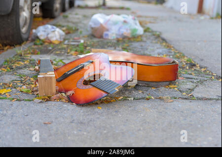 Eine kaputte alte Gitarre liegend auf dem Beton, auf einem New York City street verworfen Stockfoto