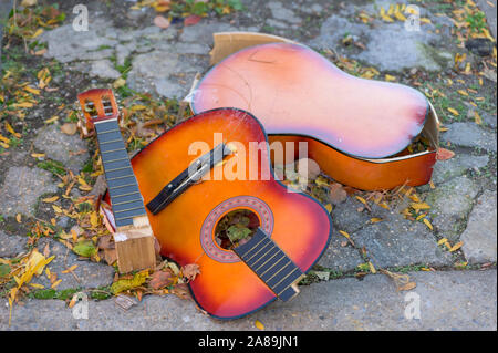 Eine kaputte alte Gitarre liegend auf dem Beton, auf einem New York City street verworfen Stockfoto