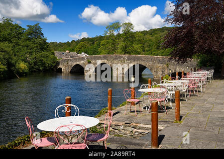 Terrasse mit Tischen und Stühlen der Swan Hotel entlang des Flusses Leven mit den fünf Bogen Newby Bridge in Lake District National Park England Stockfoto