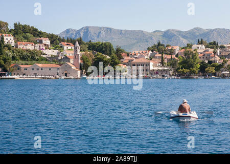 Morgen in Uvala Luka Cavtat (Cavtat Harbour), Dubrovnik-Neretva, Kroatien: Ein Mann reiht ein Schlauchboot über die Bucht. MODELL VERÖFFENTLICHT Stockfoto