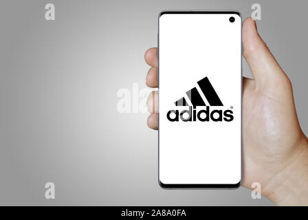 Logo der öffentlichen Unternehmen Adidas auf dem Smartphone angezeigt. Grauer Hintergrund. Credit: PIXDUCE Stockfoto