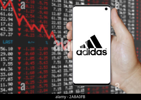 Logo der öffentlichen Unternehmen Adidas auf dem Smartphone angezeigt. Negative Börse Hintergrund. Credit: PIXDUCE Stockfoto