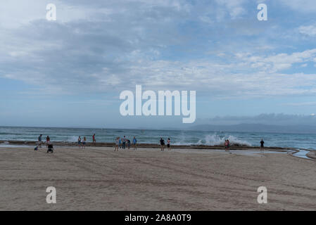 Urlauber unter selfies von Wellen am Meer Stockfoto