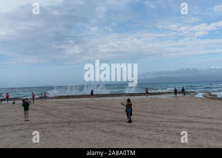 Urlauber unter selfies von Wellen am Meer Stockfoto