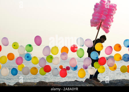 ISTANBUL - Mai 6, 2010: ein Anbieter Verkauf von Zuckerwatte auf einem Stick Spaziergänge Vergangenheit Reihen von bunten Luftballons, bespannt mit einem BB Gewehr geschossen zu werden. Stockfoto