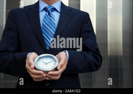 Nicht erkennbare Geschäftsmann Holding eine einfache Uhr stehen im Freien vor der modernen glänzendes Geschäft Hintergrund Stockfoto
