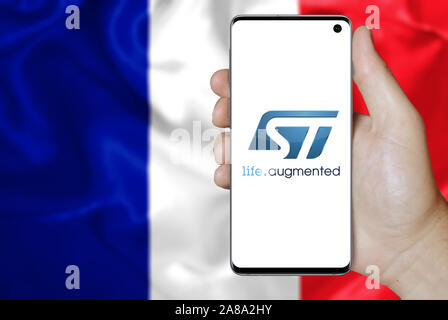 Logo der öffentlichen Unternehmen STMicroelectronics auf dem Smartphone angezeigt. Flagge Frankreichs Hintergrund. Credit: PIXDUCE Stockfoto